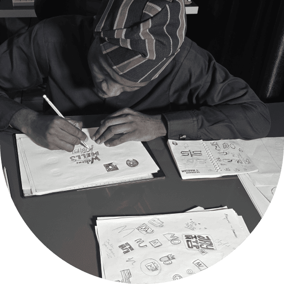 Yinka sketching logo ideas at a desk